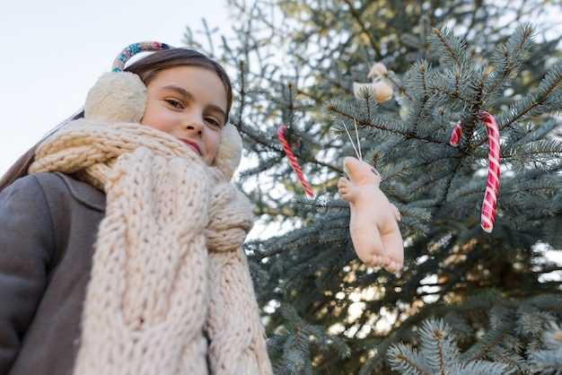 Ritratto all'aperto della bambina vicino all'albero di Natale.