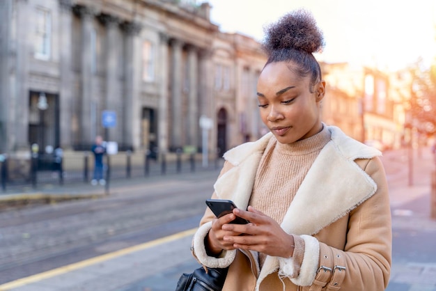 Ritratto all'aperto della donna che utilizza il telefono cellulare