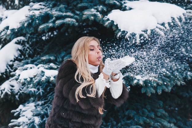 Ritratto all'aperto della ragazza di natale, neve di salto della bella donna nella foresta di inverno