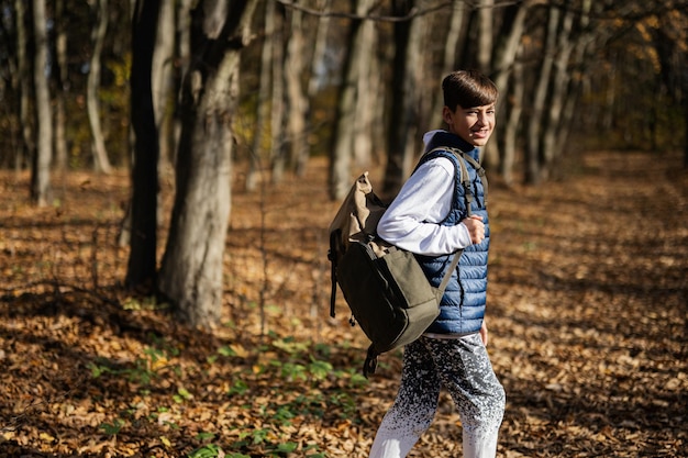Ritratto all'aperto di autunno del ragazzo dell'adolescente con lo zaino in foresta