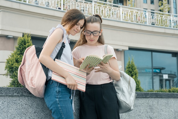 Ritratto all'aperto di due giovani belle studentesse con zaini