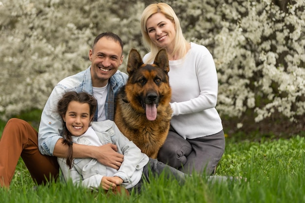 Ritratto all'aperto di giovane famiglia felice che gioca nel parco primaverile sotto l'albero in fiore, bella famiglia che si diverte nel giardino soleggiato