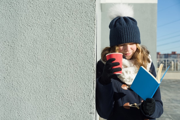 Ritratto all'aperto di inverno di giovane studentessa con il libro