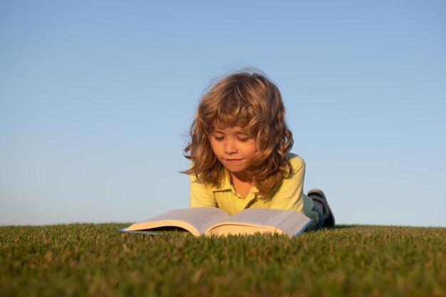 Ritratto all'aperto di un ragazzino intelligente che legge un libro