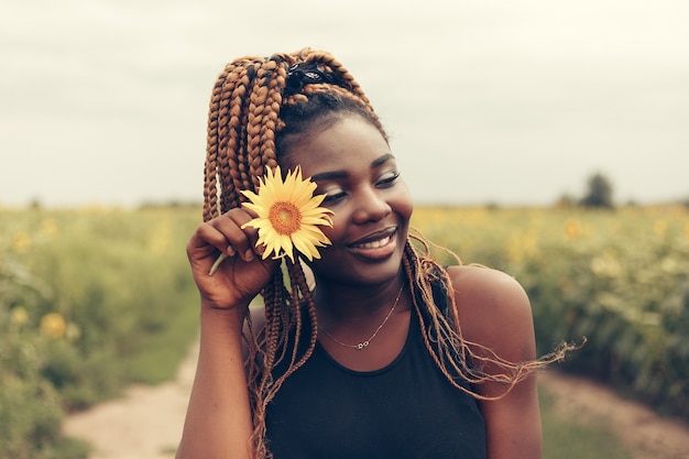 Ritratto all'aperto di una bella ragazza afroamericana in un campo di fiori gialli