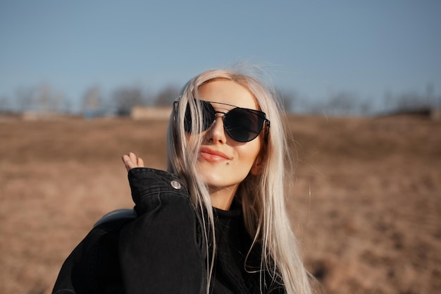 Ritratto all'aperto di una bella ragazza felice con i capelli biondi che indossa occhiali da sole
