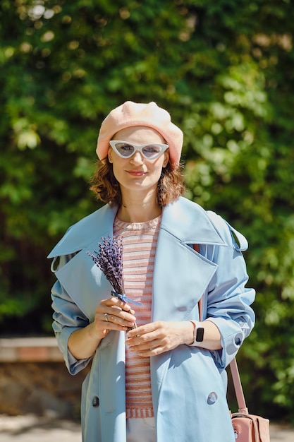 Ritratto all'aperto di una donna allegra e alla moda con la lavanda nelle mani