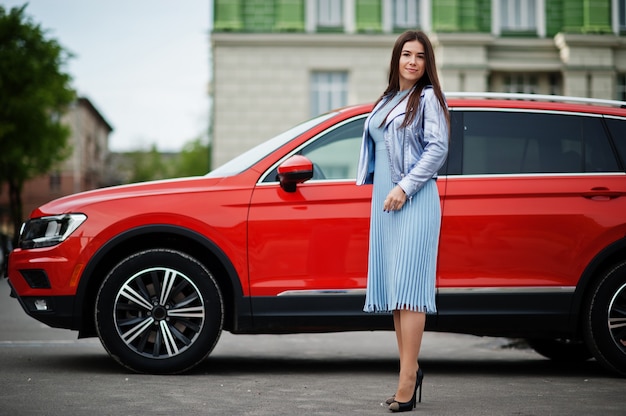 Ritratto all'aperto di una donna splendida in posa vicino a un'auto suv arancione