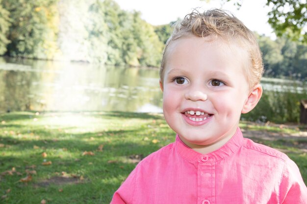 Ritratto all'aperto sorridente felice del bambino caucasico biondo al parco