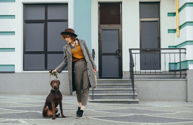 Ritratto alla moda della ragazza attraente con la posa del cane