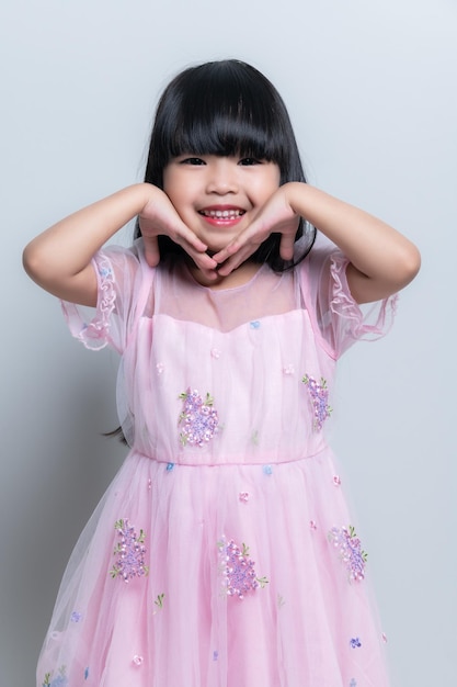 Ritratto asiatico carino bambina posa per scattare una foto in studio su sfondo bianco