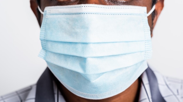 Ritratto asiatico felice giovane uomo di colore che indossa una maschera protettiva contro l'epidemia di coronavirus del virus o l'inquinamento atmosferico guardando la fotocamera, girato in studio isolato su sfondo bianco, ferma il concetto di COVID-19