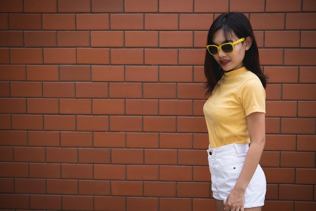 Ritratto asiatico hipster ragazza su muro di mattoni sfondoLa gente della Thailandia indossa un abito giallo