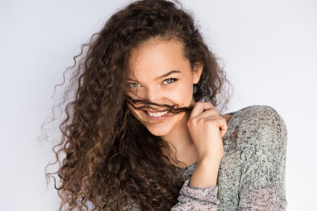 Ritratto attraente e bello della giovane donna che sorride e che fa i baffi con una ciocca di capelli