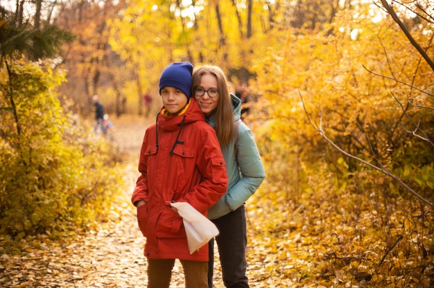 Ritratto autunnale di bella donna felice con suo figlio sullo sfondo della natura autunnale