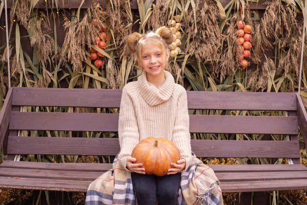 ritratto autunnale di una bella ragazza con una zucca di halloween vicino alla casa