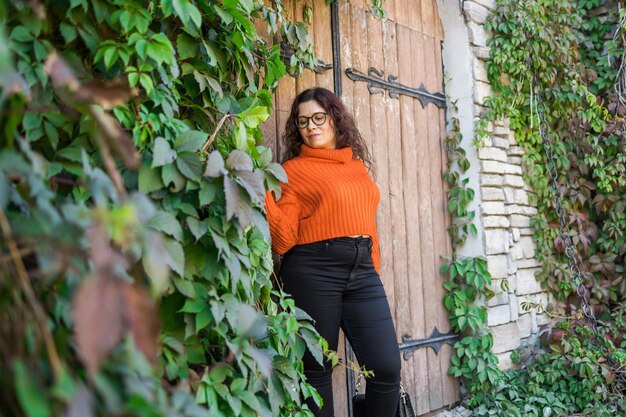 Ritratto autunnale di una giovane donna attraente con gli occhiali alla moda in un swea arancione alla moda lavorato a maglia