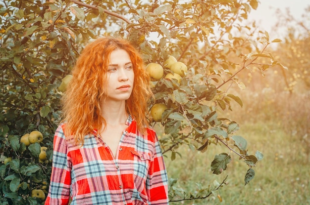 Ritratto autunnale di una giovane donna in un frutteto di mele incolto abbandonato