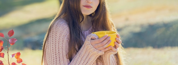 Ritratto autunnale di una ragazza con una tazza gialla