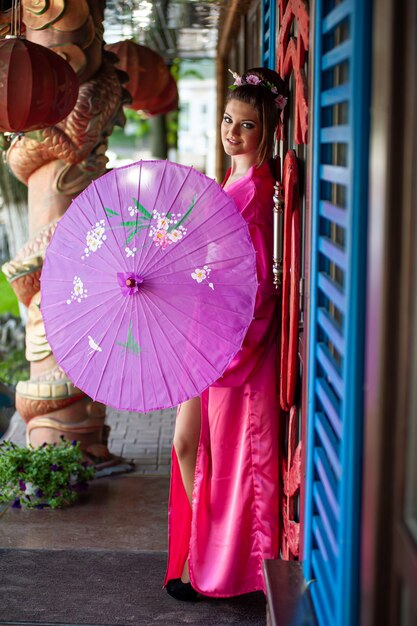 Ritratto bei sorrisi Giovane donna asiatica che indossa la decorazione cinese tradizionale rossa del cheongsam