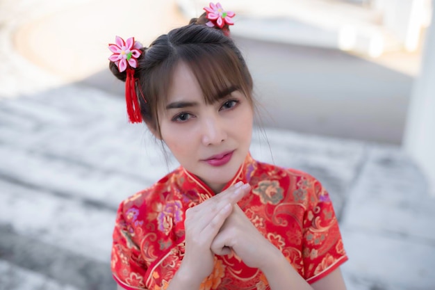 Ritratto bella donna asiatica in abito Cheongsam su sfondo biancoThailandia personeFelice anno nuovo cinese concettoFelice signora asiatica in abito tradizionale cinese