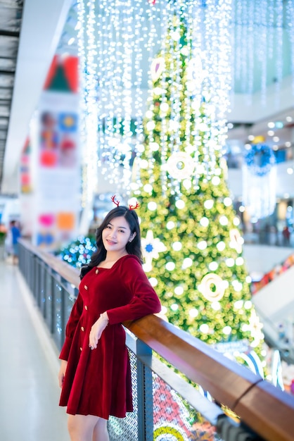 Ritratto bella giovane donna asiatica vestito rosso costume e Natale saluto foto pacchetto decorazione su albero di Natale luce circolare bokeh sfondo Decorazione durante il Natale e Capodanno.