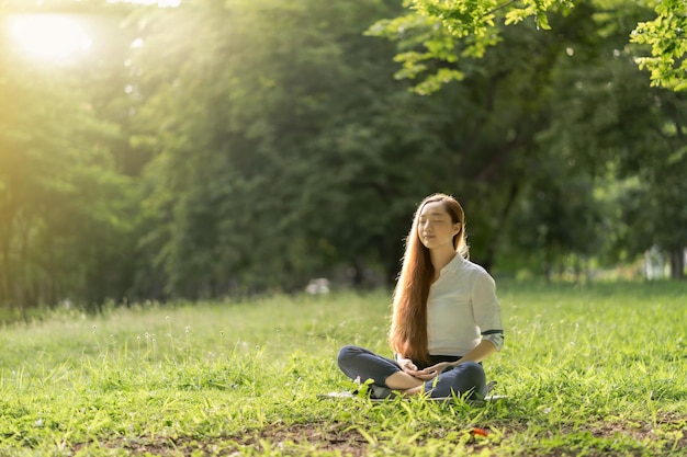 Ritratto bella giovane donna che fa meditazione in un parco all'alba in primavera o in estate