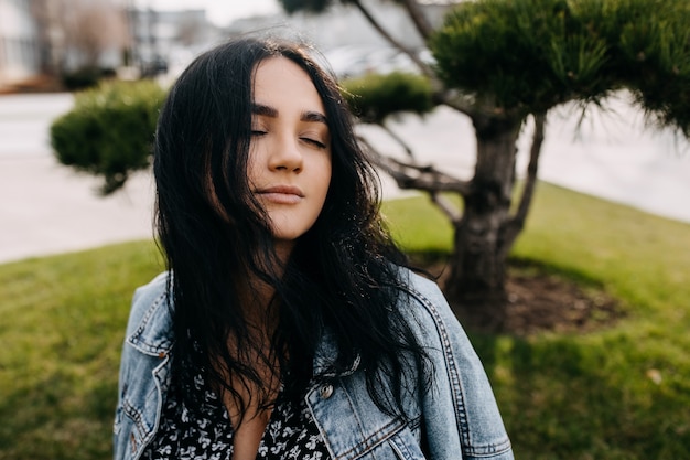 Ritratto calmo e pacifico di una giovane donna bruna che indossa una giacca di jeans