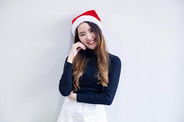 Ritratto carino giovane donna asiatica in costume di Natale e indossare il cappello rosso di Babbo Natale con un sorriso su sfondo bianco e copia spazio. Felice della donna teenager nel tema Natale.