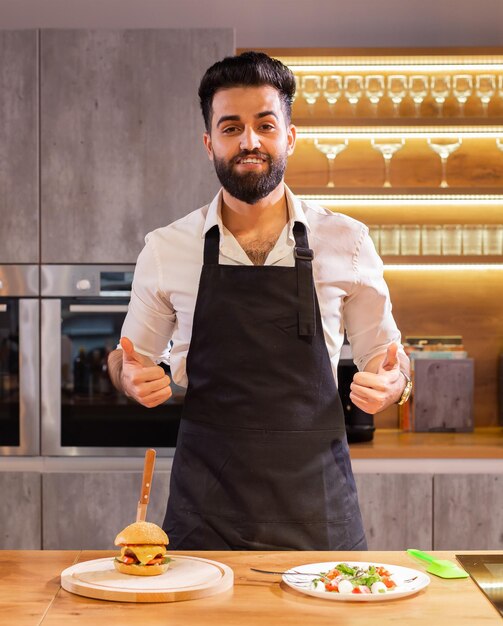 Ritratto chef felice con pasti cucinati per una cena in cucina