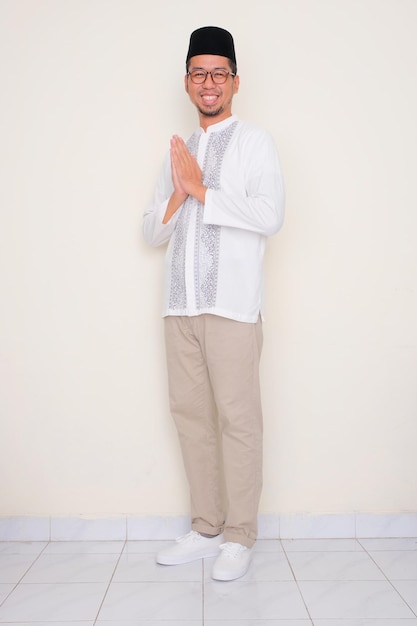 Ritratto completo del corpo di un uomo musulmano che sorride amichevolmente e fa la postura di saluto
