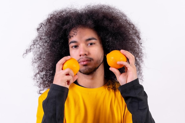 Ritratto con frutta arancione e sorridente Giovane ragazzo con i capelli afro su sfondo bianco