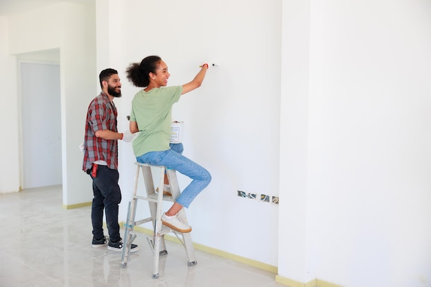 Ritratto Coppia allegra giovane uomo e donna nera sorridente durante la ristrutturazione nel nuovo appartamento Giovane famiglia felice che rinnova la casa e la pianificazione della camera da letto