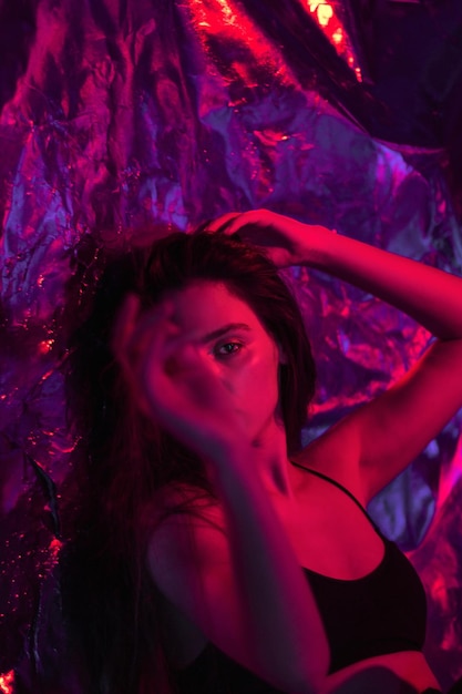 Ritratto creativo di una giovane ragazza di moda con i capelli lunghi in illuminazione al neon