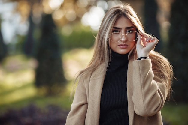 Ritratto d'autunno. Donna alla moda in occhiali immagine e cappotto nel parco