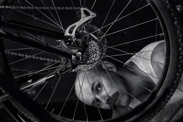 ritratto d'epoca di un uomo baffuto che ripara una ruota di bicicletta, hipster eccentrico