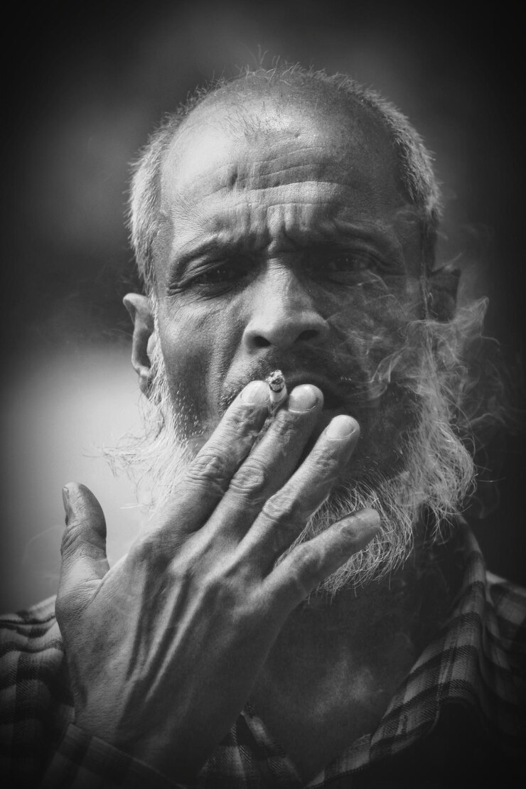 Foto ritratto da vicino di un uomo barbuto maturo che fuma una sigaretta