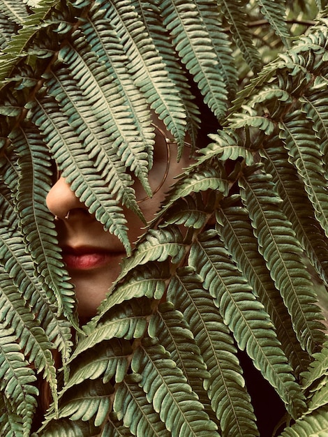 Ritratto da vicino di una giovane donna nascosta dietro le piante