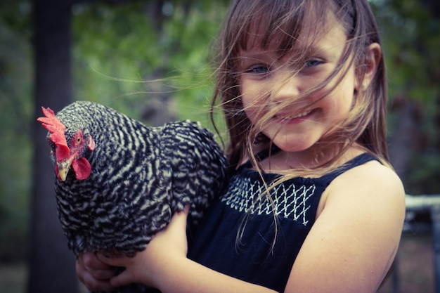 Ritratto da vicino di una ragazza sorridente che tiene un uccello pollo
