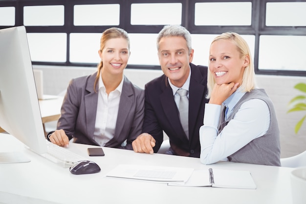 Ritratto dei professionisti sorridenti di affari che lavorano allo scrittorio del computer