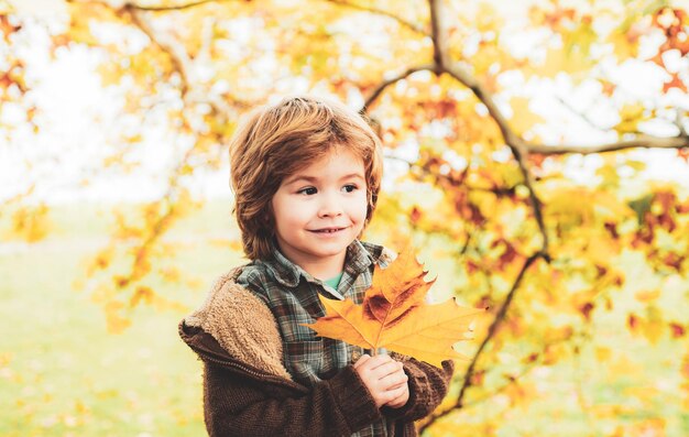 Ritratto del bambino autunnale Carino bambino felice che cattura le foglie cadute giocando nel parco autunnale