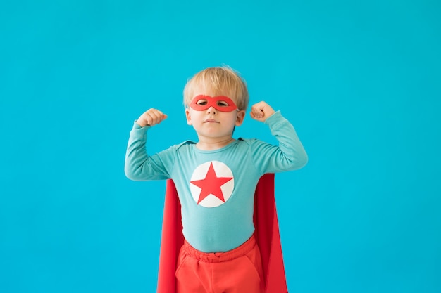 Ritratto del bambino del supereroe. Ragazzo super eroe contro il muro blu.