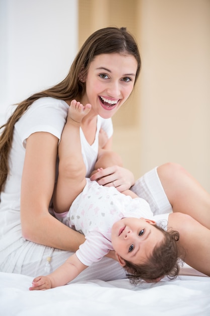 Ritratto del bambino sorridente della tenuta della madre sul letto