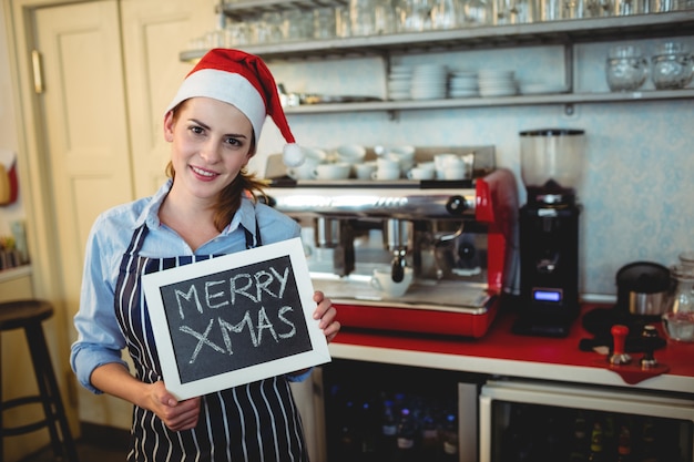 Ritratto del barista che tiene il segno di Natale al caffè