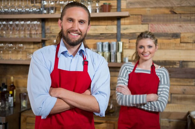 Ritratto del barista maschio sorridente con il collega femminile nella caffetteria