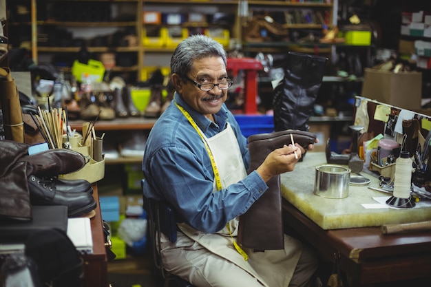 Ritratto del calzolaio sorridente che applica colla sulla scarpa