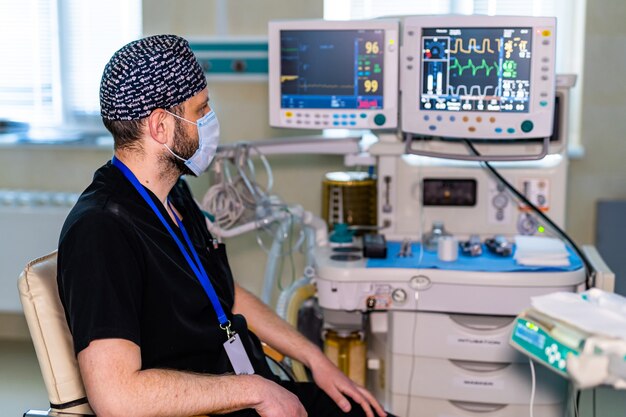 Ritratto del chirurgo professionista. Medico che indossa la maschera. Medico seduto vicino ad attrezzature professionali.