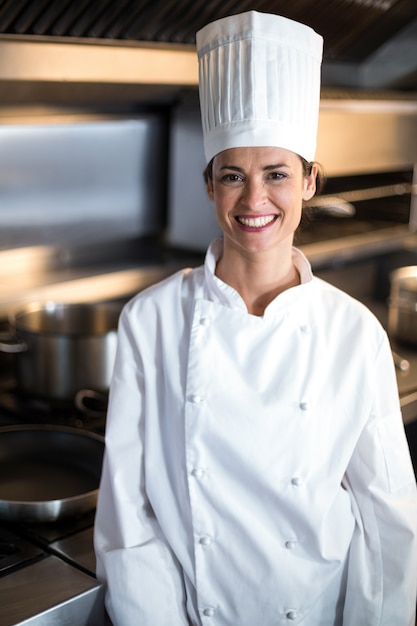 Ritratto del cuoco unico femminile sorridente che sta nella cucina