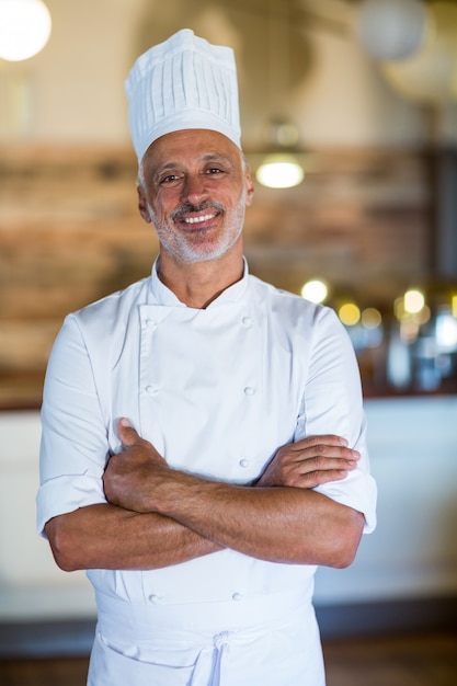 Ritratto del cuoco unico sorridente che sta con le armi attraversate