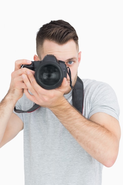 Ritratto del fotografo maschio con la macchina fotografica sopra priorità bassa bianca